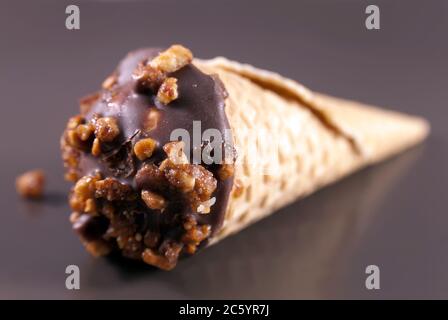 Wafer roll with cream, chocolate and nuts on a brown plate. Close up image Stock Photo