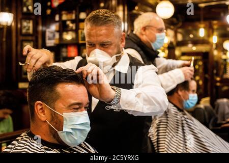 Sean Lawlor (second from left) cutting the hair of Damian Gilvary (left) at Cambridge Barbershop on Belfast's Lisburn Road, which opened at 00:01, as hairdressers and beauty salons reopen in Northern Ireland, part of the latest measure to ease coronavirus restrictions. Stock Photo