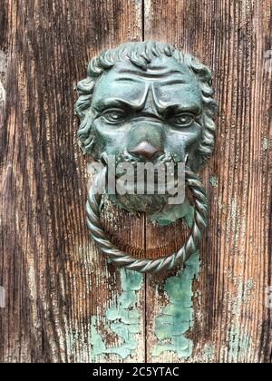 closeup lion head shaped doorknob of an old wooden door Stock Photo