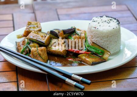 Lightly fried tofu and stew with eggplant, onion, garlic, gravy sauce on white plate, close up Stock Photo