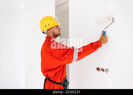 Young foreman in orange work clothes and yellow hardhat using pa Stock Photo