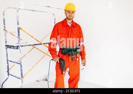 Young builder in orange work clothes and yellow hardhat looking Stock Photo