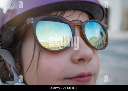 Little girl wearing mirror sunglasses at Upper Square of Badajoz. She is looking to the sky.
