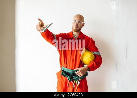 Foreman in orange work clothes and protective eyewear holding ye Stock Photo