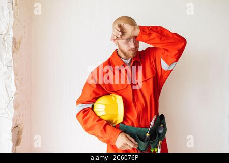 Tired foreman in orange work clothes and protective eyewear hold Stock Photo