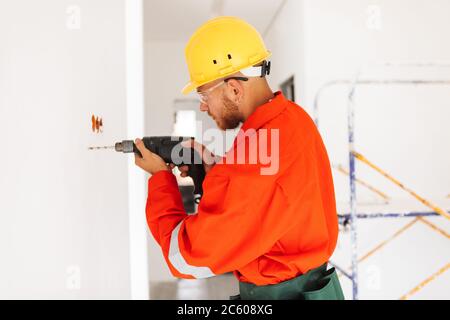 Young foreman in orange work clothes and yellow hardhat using el Stock Photo