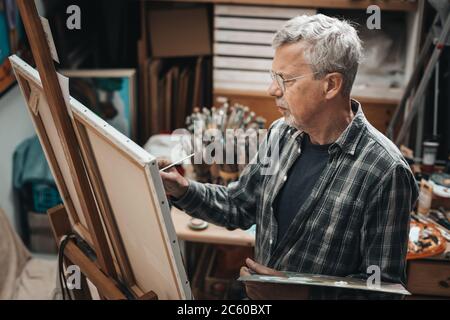 Senior artist painting in his studio Stock Photo