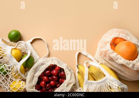Fruits and citrics in eco-friendly mesh bags on beige background. Zero waste shopping. Stock Photo