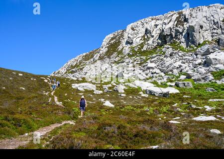 A group of walkers descends Holyhead Mountain, the highest mountain on Holy Island and in the county of Anglesey, Wales, UK. Stock Photo