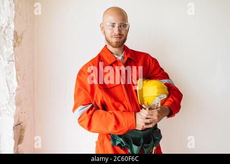 Young foreman in orange work clothes and protective eyewear hold Stock Photo