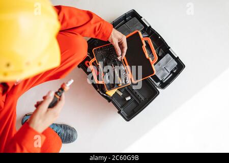 Close up builder in yellow hardhat opening chest with tools over Stock Photo