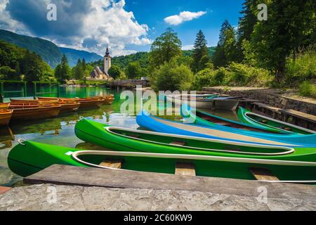 Colorful canoes, kayaks and wooden rowing boats on the lake. Recreation and sport objects on the lake Bohinj, Ribcev Laz, Slovenia, Europe Stock Photo