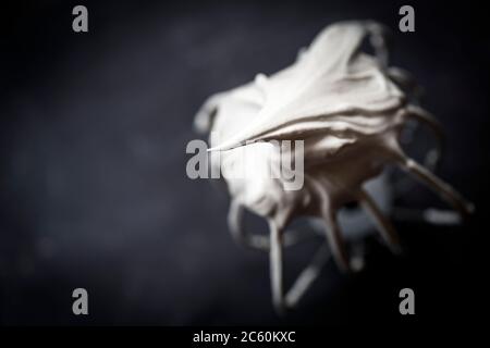 Balloon whisk coated with raw meringue, on a dark background Stock Photo
