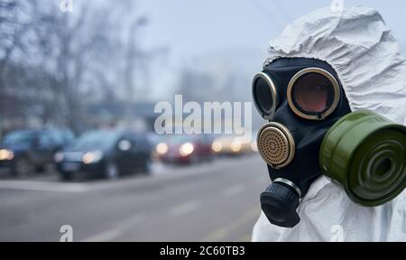 Close up of ecologist in safety respirator looking at camera while standing on the street. Research scientist wearing protective gas mask. Concept of ecology, radiation and environmental pollution.
