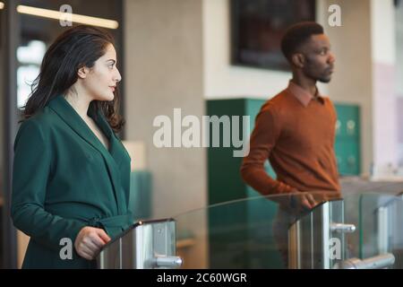 Side view portrait of young Middle-Eastern woman passing automated gate while entering office building, copy space Stock Photo