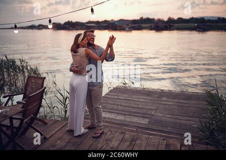 young happy couple dancing by the river at sunset Stock Photo