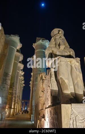 Ancient sitting statue of Ramses II in Luxor Temple lit up at night ...