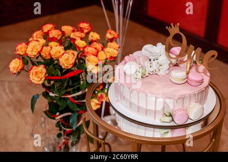 Festive cake on a stand and a bouquet of orange roses Stock Photo