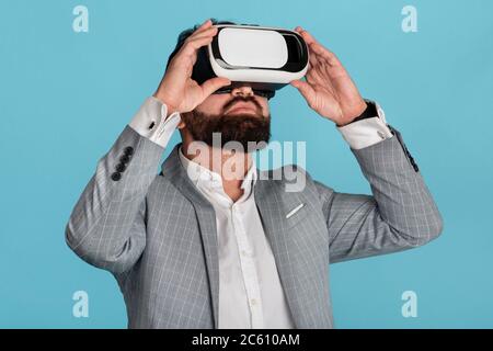 Businessman in virtual reality headset exploring cyberspace on blue background Stock Photo