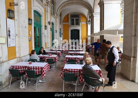 LISBON, PORTUGAL - JUNE 4, 2018: People visit shaded arcades of Comercio Square (Praca Comercio) in Lisbon, Portugal. Lisbon is the 11th-most populous Stock Photo