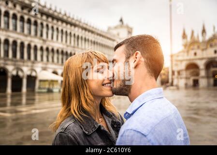 Beatiful young couple having fun while visiting Venice - Tourists travelling in Italy and sightseeing the most relevant landmarks of Venezia - Concept Stock Photo