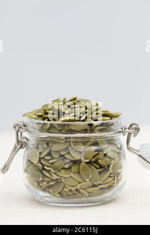 organic pumpkin seeds in glass jar on gray background. Concept of healthy diet. Super food. copy space selective focus Stock Photo