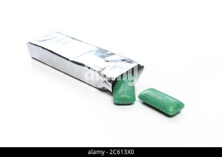 Green chewing gums and bright package isolated on white. Silver paper foil for mint bubblegums Stock Photo