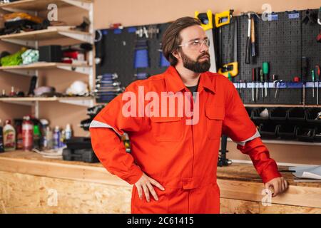 Builder in work clothes and protective eyewear thoughtfully look Stock Photo