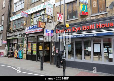 LONDON, UK - APRIL 22, 2016: People walk by ethnic stores and restaurants at Brick Lane, Shoreditch, London. Shoreditch is known for its multicultural Stock Photo