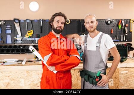 Two builders in work clothes thoughtfully looking in camera spen Stock Photo