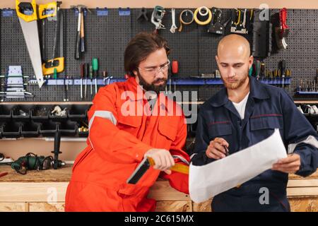 Two builders in work clothes thoughtfully working on sketch with Stock Photo