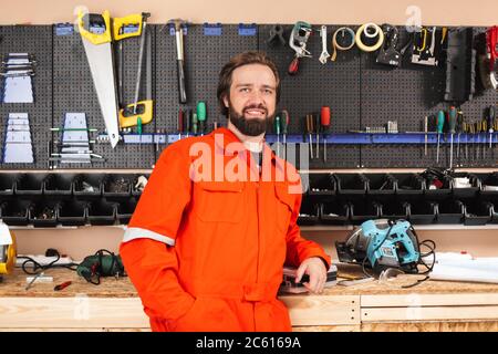 Smiling foreman in orange work clothes happily looking in camera Stock Photo