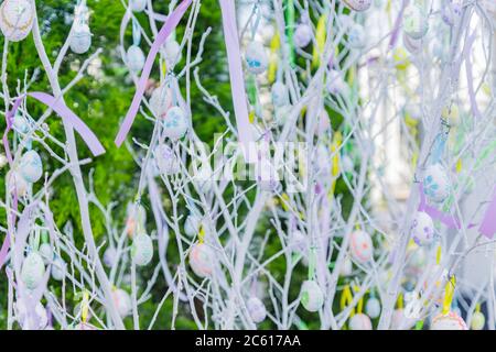 easter eggs hanging on white tree branches, colorful background Stock Photo