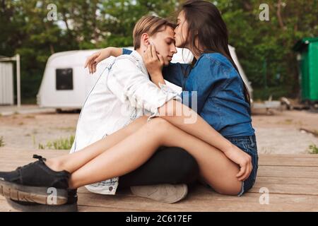 Portrait of young pensive couple sitting and embracing one another while spending time together in park Stock Photo
