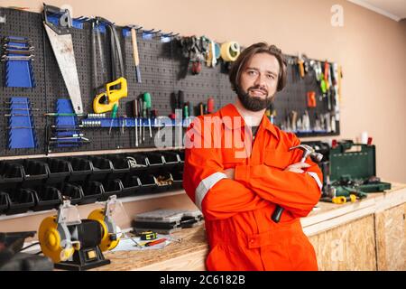 Smiling foreman in work clothes holding hammer in hand happily l Stock Photo