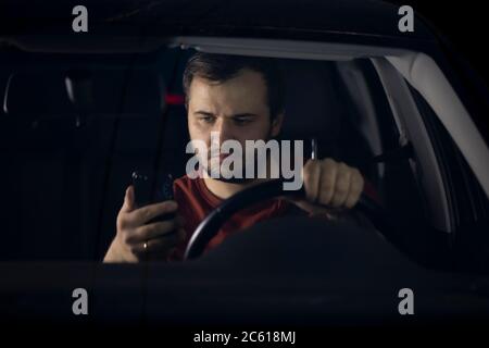 sad driver sits at car at night tired looking at smartphone worried on problems Stock Photo