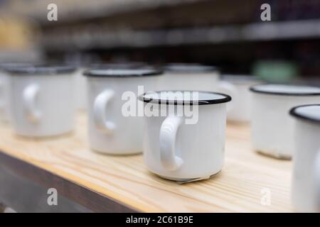 white metal enameled mugs standing on a store counter Stock Photo