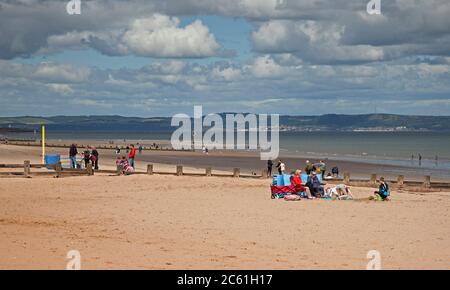 Portobello, Edinburgh, Scotland, UK. 6 July 2020. Temperature 16 degrees centigrade by noon encouraged people to get out,a few people brought windbreaks to the seaside to relax on the sandy beach. Stock Photo