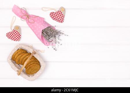 Lavender flower bouquet with cookies in basket on white wooden table. Top view, copy space. Rustic background Stock Photo