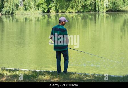 An Asian American man fishes in the Lake at Kissena Park in Flushing, Queens, New York City. Stock Photo