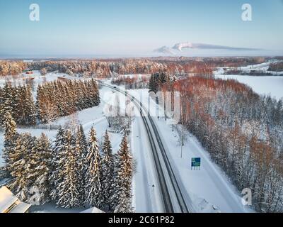 The road passes on the outskirts of the Finnish city of Joensuu, winter, a lot of snow, in the blue sky the moon Stock Photo