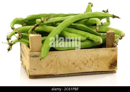 bunch of broad beans in a wooden box on a white background Stock Photo