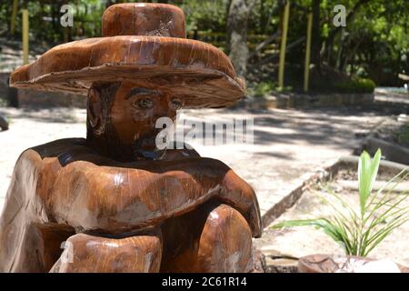 Man carved in hardwood, entirely handcrafted, man wearing a hat with his arms crossed, contemplating nature in an ecotourism farm in Brazil, South Ame Stock Photo
