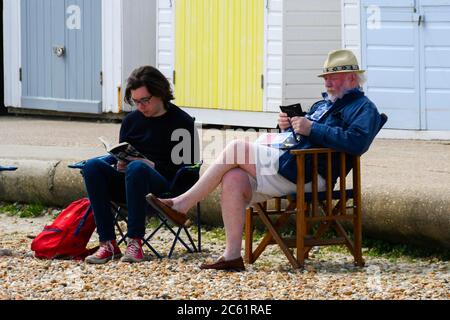 Lyme Regis, Dorset, UK.  6th July 2020.   UK Weather:  Two men sitting in chairs on the beach at the seaside resort of Lyme Regis in Dorset on a day of warm sunny spells.  Picture Credit: Graham Hunt/Alamy Live News Stock Photo