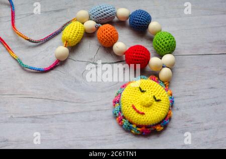 Necklace made from knitted beads and toys for the baby sitting in a sling. Knitted beads. Sling necklace. Stock Photo