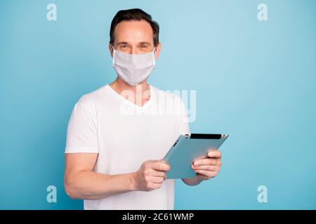 Portrait of his he nice skilled guy wearing safety n95 mask using holding in hand tablet device browse read flu china wuhan mers cov infection Stock Photo