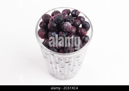 Glass full of frozen blueberries, frost glass, white background. Close up, top view Stock Photo