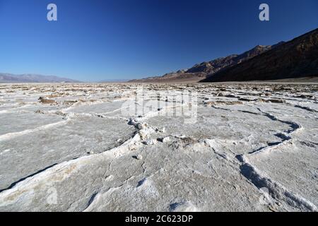 The salt flats of Badwater Basin in Death Valley National Park.  The white salt is seen with mountains from the Amargosa range rising from the ground.