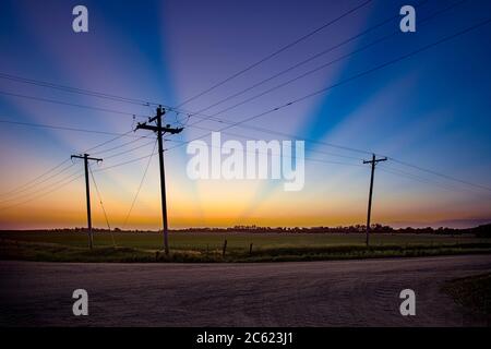 Colorful beams of light at sunset with three utility poles - a modern day Calgary Stock Photo