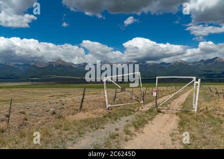 Old worn weathered rusty metal gate with rocky mountains, Colorado USA Stock Photo